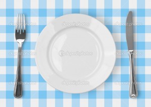 Knife, white plate and fork on blue checked tablecloth