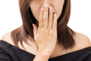 Scared young woman with her hand on her mouth